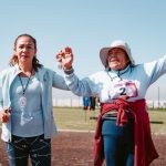 Elderly woman celebrates completing an outdoor race, showcasing joy and achievement.