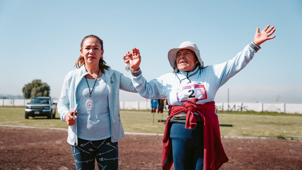 Elderly woman celebrates completing an outdoor race, showcasing joy and achievement.